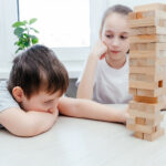 Caucasian children, boy and girl playing jenga. Block stacking game