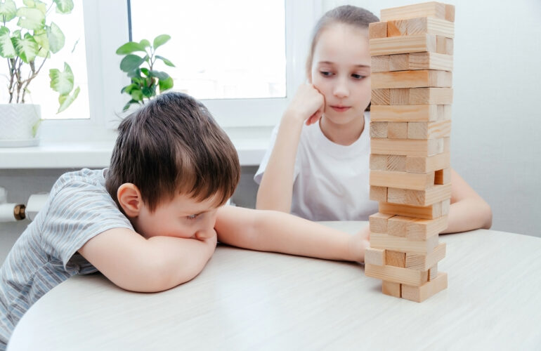 Caucasian children, boy and girl playing jenga. Block stacking game